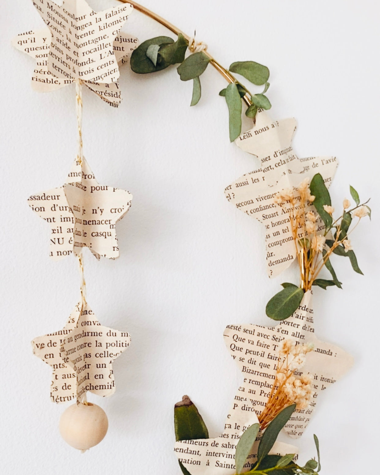 Couronne poétique et écologique en papier recyclé et végétaux séchés, parfaite pour décorer la maison avec délicatesse. Ses étoiles en papier de livre rappellent les objets vintage et empreints d’histoire, tandis que les fleurs et feuilles séchées ajoutent une touche végétale naturelle. Idéale en décoration de Noël ou comme décoration murale en toute saison. Fabriquée à la main en France, chaque pièce est unique et chargée de sens. ninona