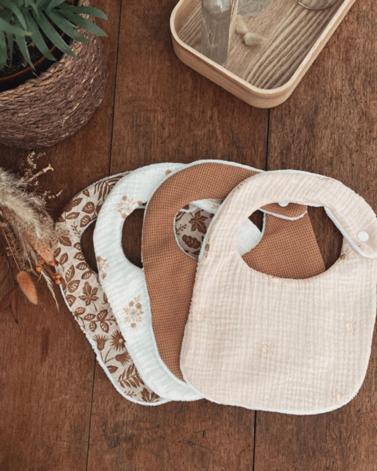 Lot artisanal de bavoirs bébé faits main en coton, gaze de coton et tissu absorbant. Chaque bavoir est doux, pratique et confortable pour la peau délicate de bébé. Fermeture par bouton pression sécurisée, idéale dès la naissance. Motifs assortis aux tons naturels et floraux bohèmes. Un lot de bavoirs élégants et absorbants, parfaits pour les repas ou les bavouilles quotidiennes. Accessoire pratique et esthétique, idéal comme cadeau de naissance ou baby shower
