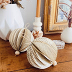 Ces boules légères sont nées de pages oubliées, patinées par le temps. Chaque feuille de vieux livre a été découpée, pliée et assemblée à la main, révélant une douce harmonie entre papier ancien, ficelle naturelle et perle de bois. Parfaites pour une décoration poétique et durable, elles apportent une touche d’authenticité et de charme à tout intérieur. ninona