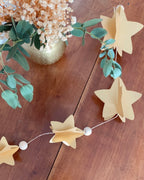 Guirlande décorative d’étoiles papier en 3D, avec perles en bois, suspendue le long d’un grand miroir doré. Ambiance chaleureuse et élégante pour une décoration intérieure intemporelle. Fait main en France avec patience et délicatesse. Convient aussi bien à la décoration de Noël qu’à la décoration quotidienne. Apporte une touche poétique, douce et lumineuse à votre intérieur. ninona