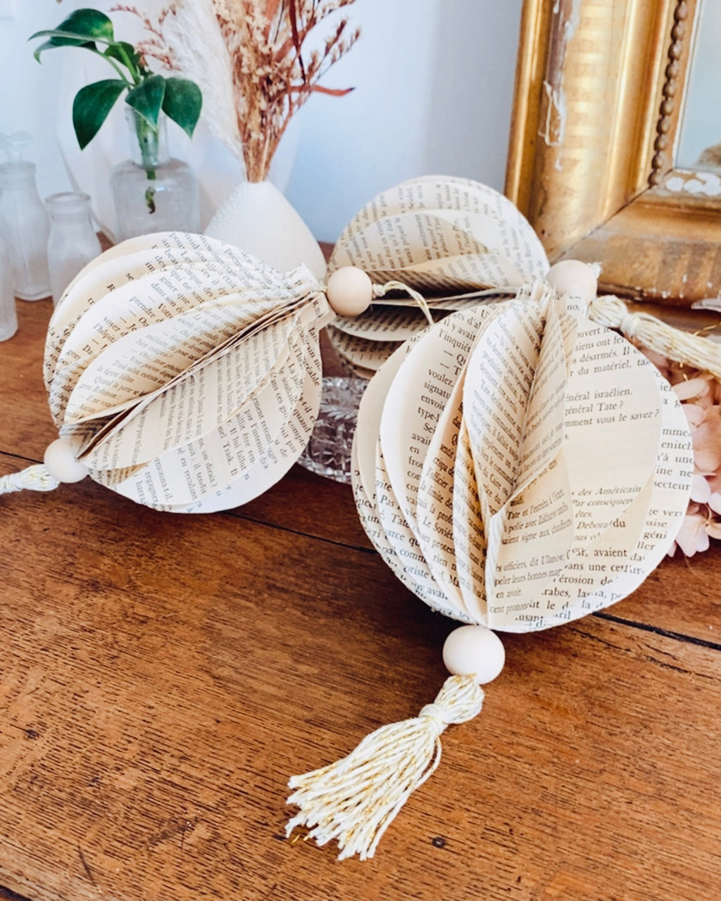 Pour un Noël éco-responsable, misez sur une décoration artisanale et durable. Cette boule de Noël est réalisée à la main à partir de papier recyclé issu de livres anciens. Ses matériaux naturels — jute et perles de bois — lui donnent une allure poétique et intemporelle. Chaque pièce est unique, témoignant du charme du fait main et d’une démarche créative respectueuse de la planète. ninona