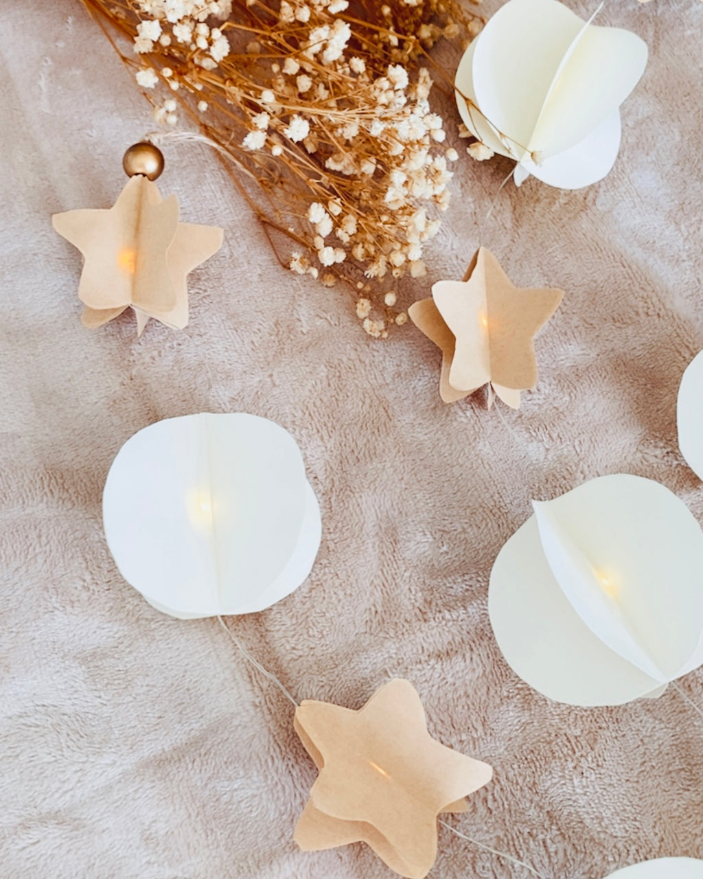 Création artisanale en papier comprenant une alternance d’étoiles kraft et de disques blancs, répartis harmonieusement le long d’un fil lumineux. Les LED apportent une clarté douce qui se diffuse à travers les formes pliées. Cette guirlande, entièrement faite main, offre un charme authentique et poétique, parfaite pour une décoration d’intérieur naturelle, chaleureuse ou festive. ninona
