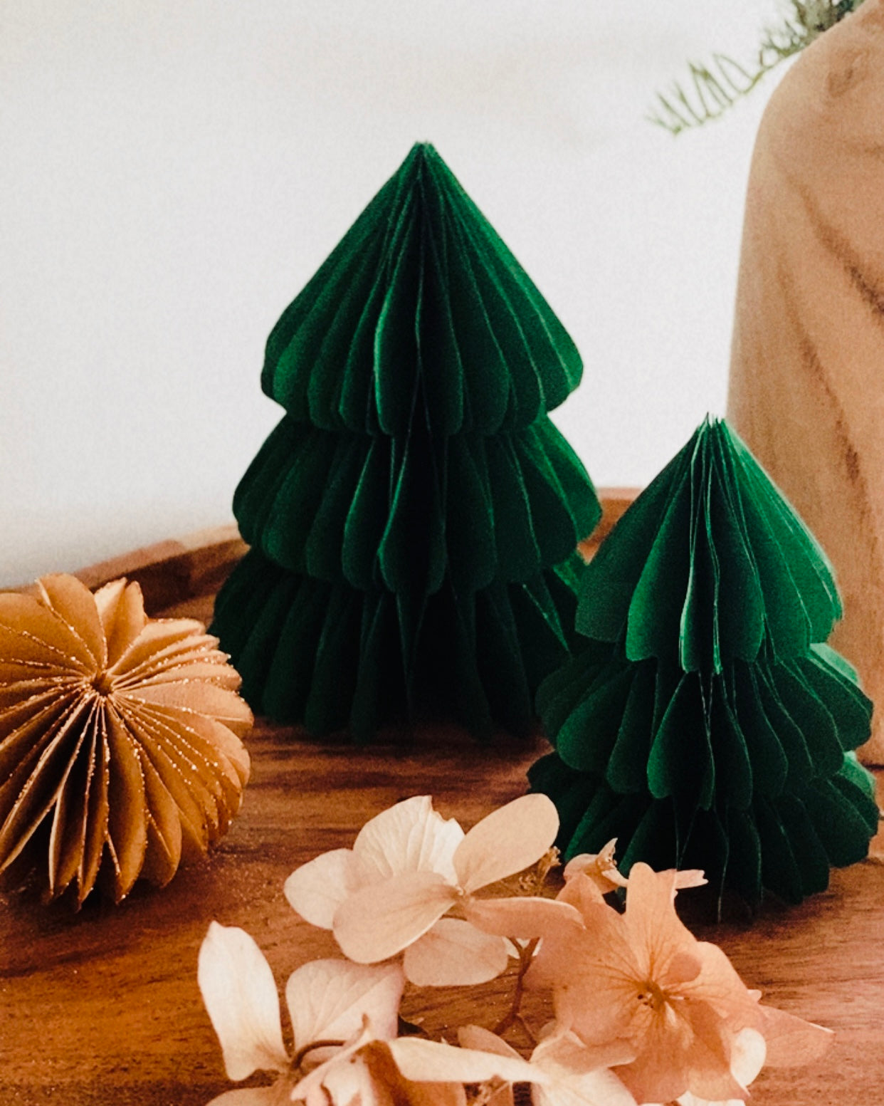 Lot de deux sapins en papier faits main, en vert émeraude, posés sur un plateau en bois dans une ambiance douce et chaleureuse. Ces décorations artisanales de Noël apportent une touche poétique et naturelle à votre intérieur. Idéal pour compléter une décoration de table, créer un village d’hiver miniature ou offrir un cadeau fait avec soin. ninona