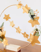 Couronne poétique réalisée à la main, composée de fleurs séchées blanches, de feuilles d’eucalyptus et d’étoiles dorées montées sur un cerceau métallique. Peut être suspendue au mur ou posée grâce à son socle en bois. Décoration artisanale made in France, parfaite pour Noël, une entrée, une chambre ou un salon. Idée cadeau créative pour celles et ceux qui aiment la décoration naturelle, minimaliste et chaleureuse. ninona