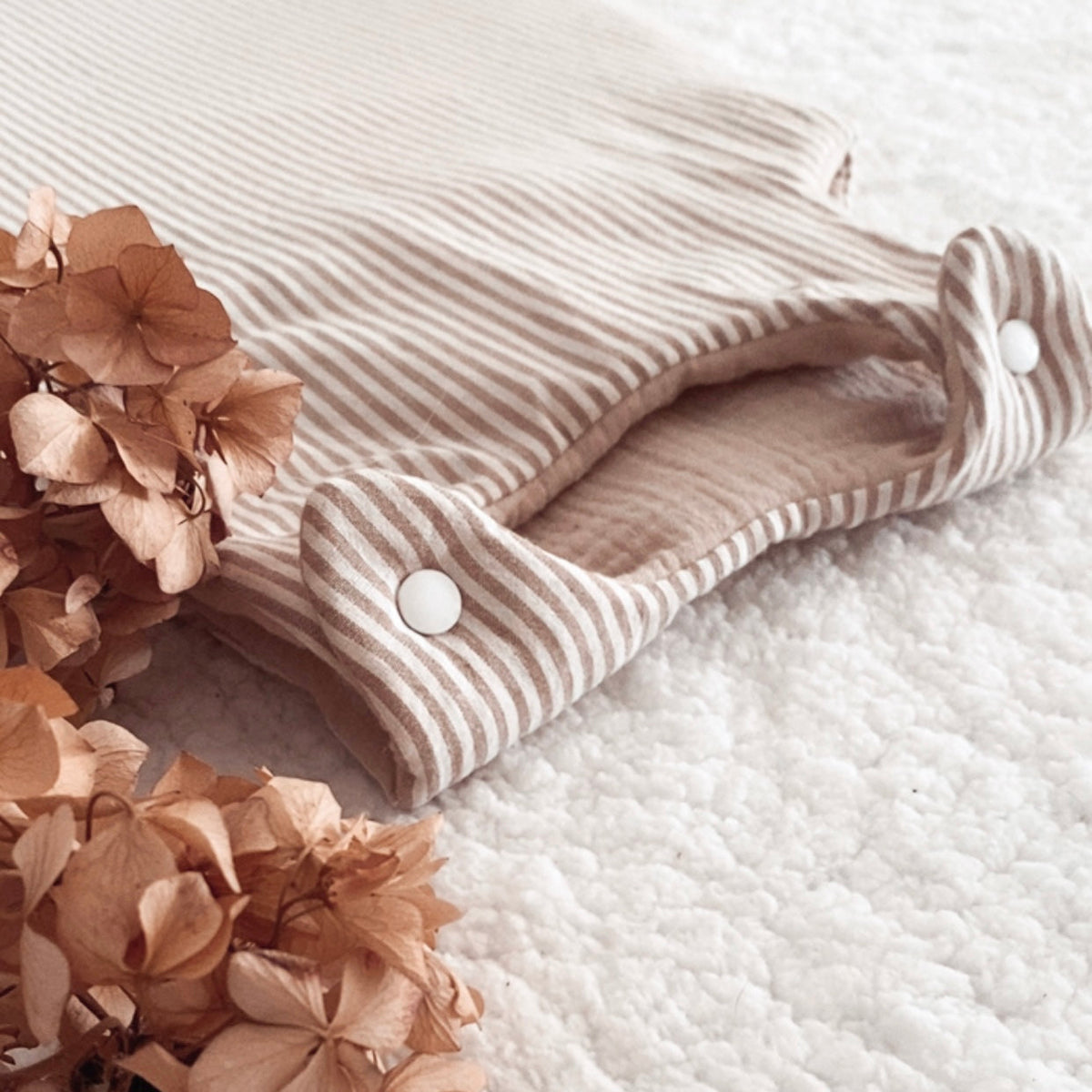 Gigoteuse bébé artisanale à rayures beige et écru, confectionnée avec soin à la main. Son style doux et intemporel s’accorde parfaitement à l’univers de bébé. Cette gigoteuse personnalisable peut être réalisée selon vos envies et convient aux filles comme aux garçons. Disponible en plusieurs tailles et en trois versions : été, mi-saison ou hiver, elle accompagne bébé au fil des saisons dans un cocon confortable et douillet. Idée cadeau de naissance originale et personnalisée. Ninona