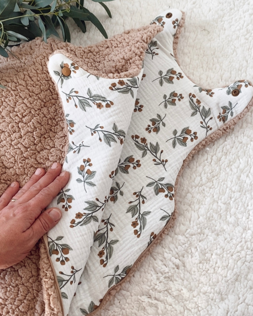 Vue détaillée de l’intérieur de la gigoteuse bébé 0/6 mois hiver. La double gaze de coton blanc cassé est imprimée de délicats motifs végétaux aux tons naturels, avec de petites branches, feuilles et baies brunes et vertes. Le sherpa chocolat forme un bord tout doux autour de la turbulette. Cette gigoteuse TOG 2 artisanale offre une ambiance chaleureuse et poétique, parfaite pour les nuits fraîches et pour créer un joli univers naturel autour de bébé. Une création artisanale pensée pour bébé. Ninona