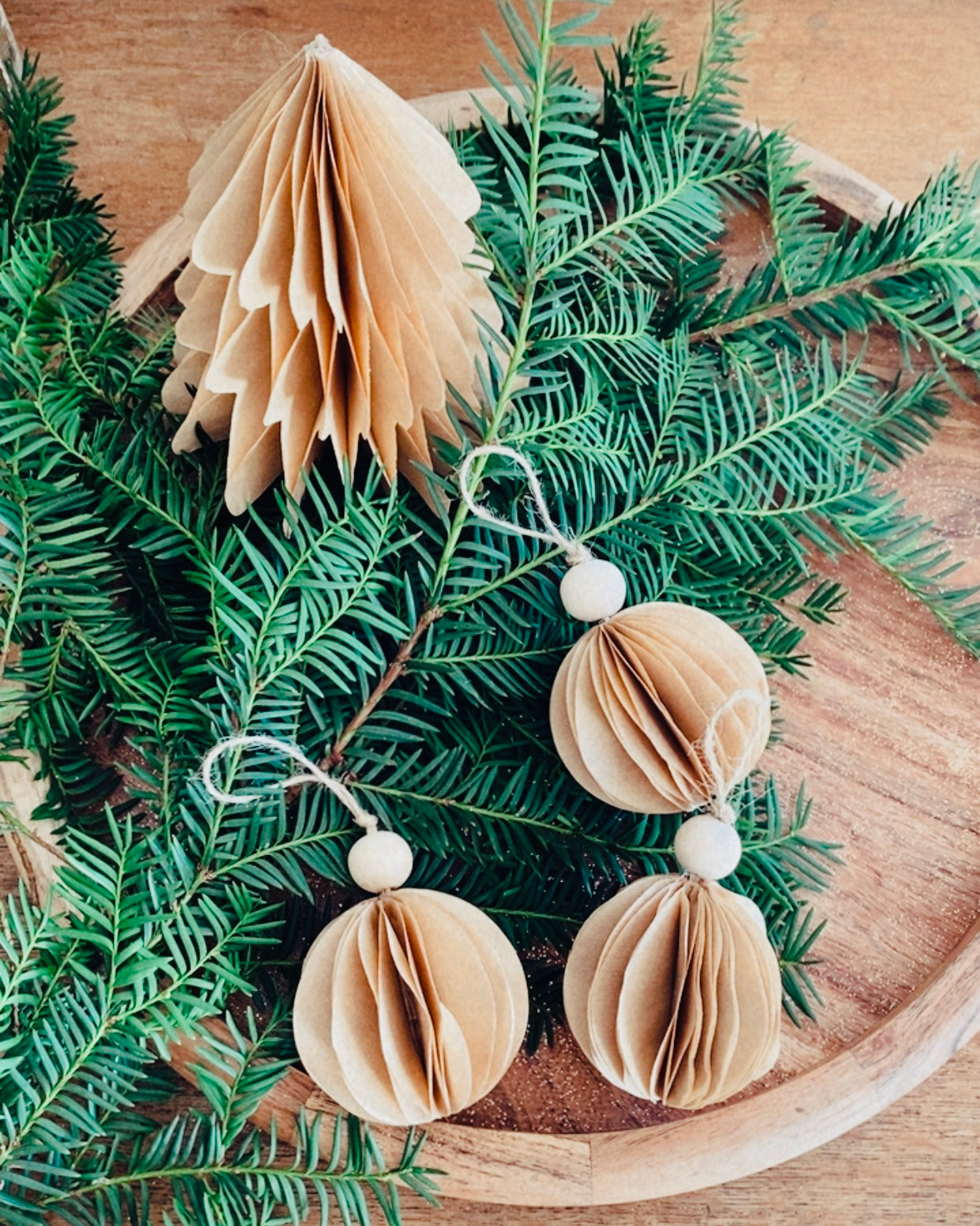 Petit sapin en papier fait main, présenté en décor de Noël naturel. Chaque pièce est unique, réalisée avec soin artisanal. Ces sapins décoratifs ajoutent une touche chaleureuse et poétique, idéale pour une décoration de table ou une ambiance douce et hivernale dans la maison. ninona