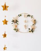 Vue rapprochée d’une guirlande d’étoiles artisanale en papier, chaque étoile découpée et collée à la main pour créer un relief 3D. Perles en bois et fil doré complètent cette décoration naturelle et raffinée. Parfaite pour chambre d’enfant, coin lecture, salon ou ambiance festive de Noël. Fabrication française, unique et poétique. ninona