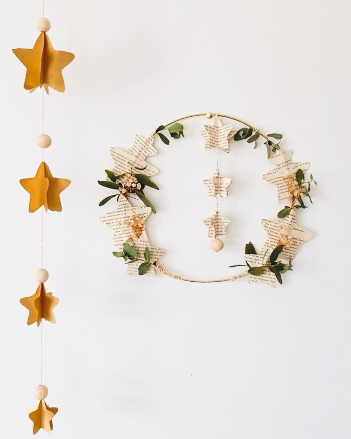 Vue rapprochée d’une guirlande d’étoiles artisanale en papier, chaque étoile découpée et collée à la main pour créer un relief 3D. Perles en bois et fil doré complètent cette décoration naturelle et raffinée. Parfaite pour chambre d’enfant, coin lecture, salon ou ambiance festive de Noël. Fabrication française, unique et poétique. ninona