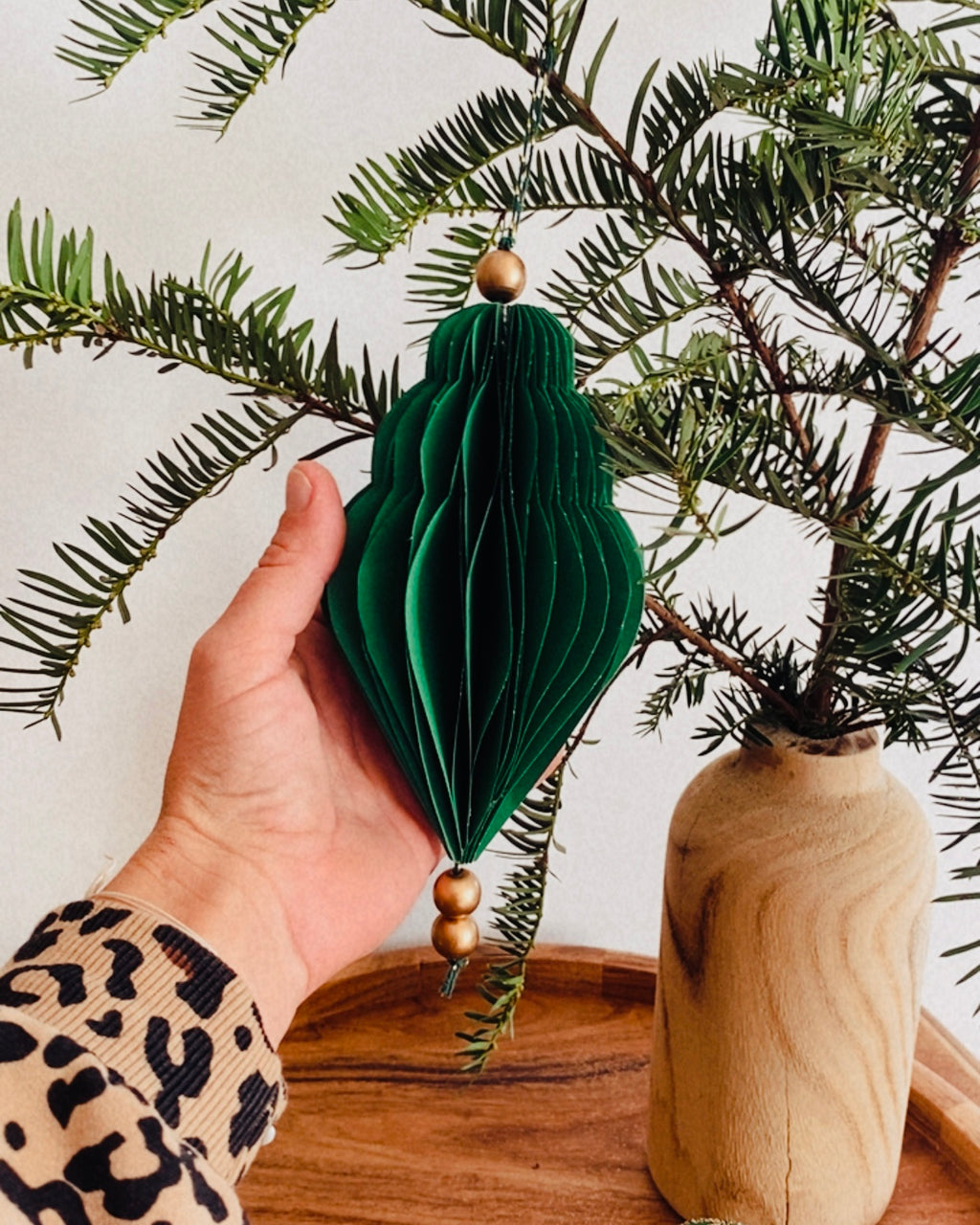 Ornements de Noël faits main en papier, présentés dans une coupe en bois garnie de branches de sapin. Les boules sont de différentes formes et couleurs : vert émeraude profond et écru chaleureux. Certaines sont rehaussées de fines paillettes dorées. L’ensemble évoque une décoration naturelle, authentique et poétique, parfaite pour un Noël doux, artisanal et inspiré par la nature. ninona