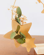 Décoration artisanale élégante : couronne en métal doré ornée de fleurs séchées et de feuilles d’eucalyptus, embellie de petites étoiles dorées. Création faite main en atelier en France. Peut être accrochée en décoration murale ou présentée sur un socle en bois. Parfaite pour une ambiance douce à Noël ou tout au long de l’année. Cadeau idéal pour les amateurs de décoration naturelle et poétique. ninona