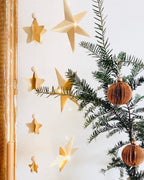 Guirlande d’étoiles en papier doré fixée près d’un miroir ancien. Lumière LED douce créant une ambiance chaleureuse et accueillante. Chaque étoile est réalisée à la main avec soin, inspirée de l’artisanat et de la décoration naturelle. Parfait pour le salon, une chambre d’enfant, ou pour créer une atmosphère de Noël douce et lumineuse. Décoration élégante et poétique. ninona