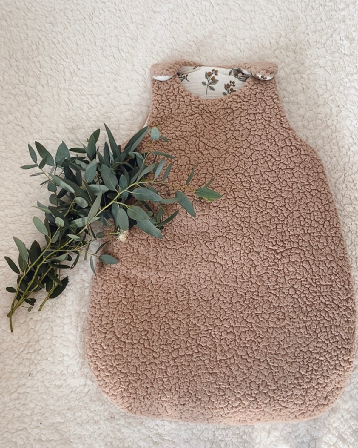 Gigoteuse bébé hiver 0/6 mois en sherpa chocolat, douce et chaleureuse, entièrement confectionnée à la main. L’extérieur en sherpa offre un aspect moelleux et cocooning, tandis que l’intérieur en double gaze de coton blanc cassé est délicatement imprimé de motifs végétaux bruns et gris. Cette turbulette bébé TOG 2 est idéale pour les nuits fraîches. Une création artisanale et poétique, pensée pour apporter douceur et confort au sommeil de bébé. Une création artisanale faite main, avec amour. Ninona
