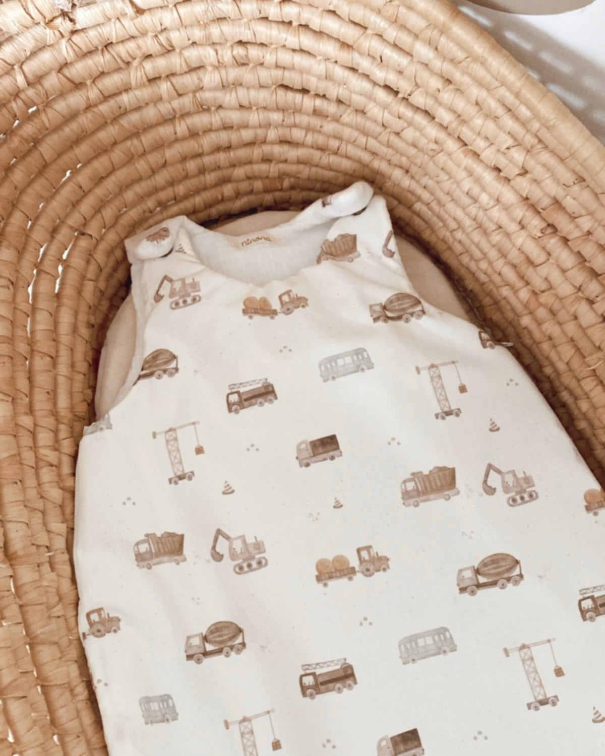 Gigoteuse bébé 0/6 mois mi-saison TOG 1, confectionnée artisanalement avec un extérieur en popeline de coton blanc cassé imprimée de petits engins de chantier dans des tons bruns et une doublure intérieure en double gaze de coton blanc cassé. Cette turbulette douce et confortable présente un joli style naturel et intemporel. Modèle unique disponible, idéal comme cadeau de naissance pour un petit garçon. Ninona
