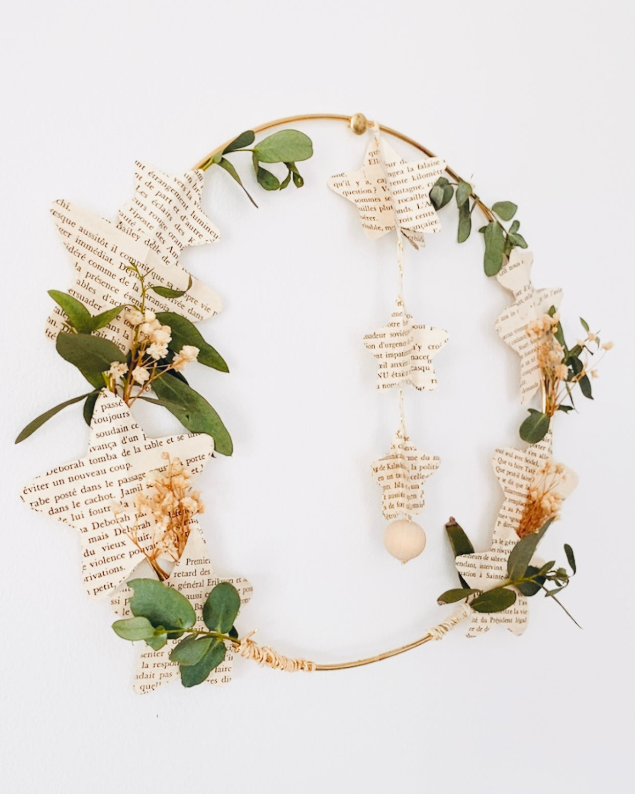 Couronne de Noël naturelle et originale, réalisée avec des pages de livres anciens, de la gypsophile séchée et de l’eucalyptus. Son design aérien évoque la légèreté et la douceur des fêtes. Elle peut être accrochée au mur, posée sur une étagère ou utilisée pour décorer la table de fête. Cette décoration écoresponsable apporte une touche vintage et poétique à votre intérieur. Fait main en France avec des matériaux soigneusement sélectionnés. ninona
