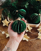 Composition festive réunissant boules de Noël artisanales, plateau en bois et branches de sapin naturel. Le décor évoque la simplicité d’un Noël fait maison, avec des matières naturelles, du papier, du bois et de fines touches dorées. L’ensemble transmet une ambiance calme, chaleureuse et poétique. ninona