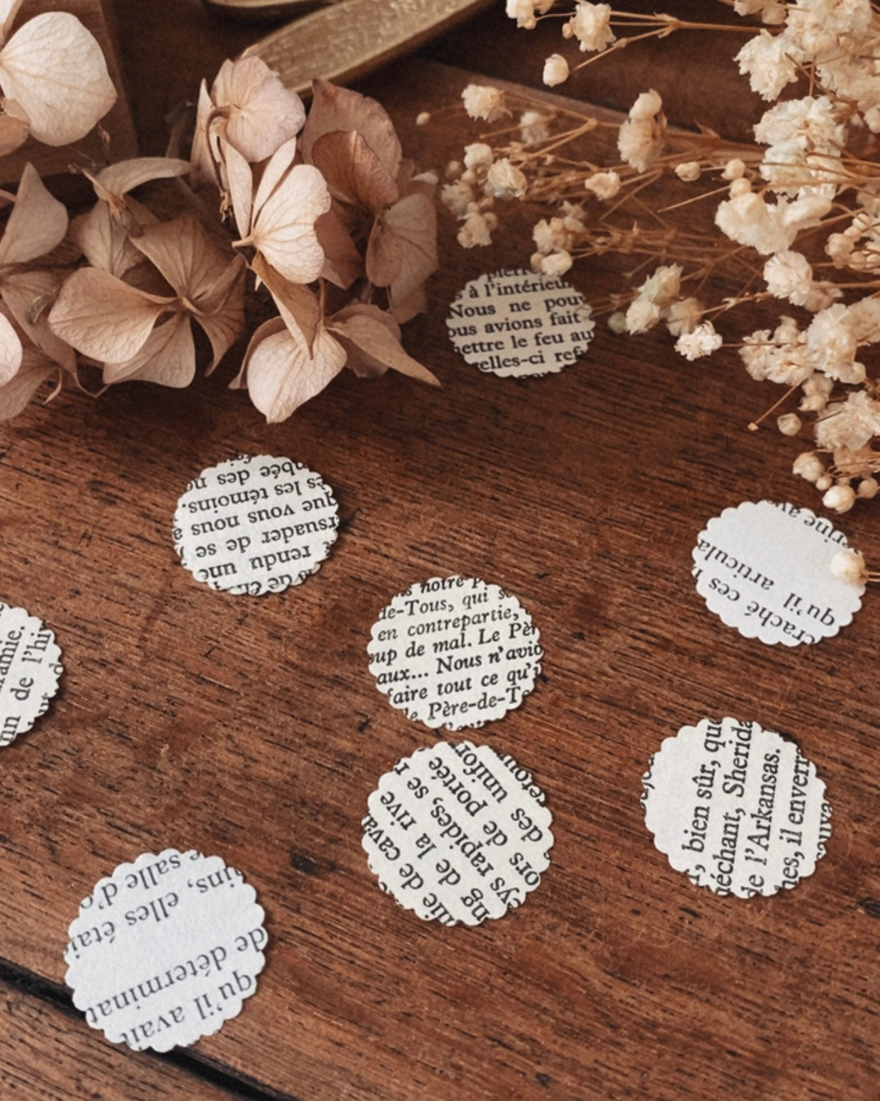 Confettis en pages de livres vintage disposés sur une surface décorative, évoquant une table de réception ou une mise en scène festive. Le papier ancien et les textes imprimés créent une atmosphère romantique, douce et littéraire. Ces confettis sont parfaits pour une décoration de mariage bohème, une fête élégante ou un événement à thème vintage, tout en respectant une démarche éco-responsable. ninona creation