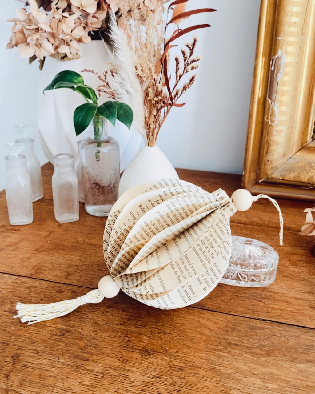 Cette boule décorative en papier de vieux livres est une pièce artisanale unique, réalisée dans une démarche d’upcycling et de création responsable. Faite main, elle apporte une atmosphère douce et naturelle à votre décoration de Noël. À suspendre ou poser, elle s’intègre parfaitement dans une ambiance bohème, vintage ou minimaliste. Un Noël plus authentique et éco-conscient. ninona