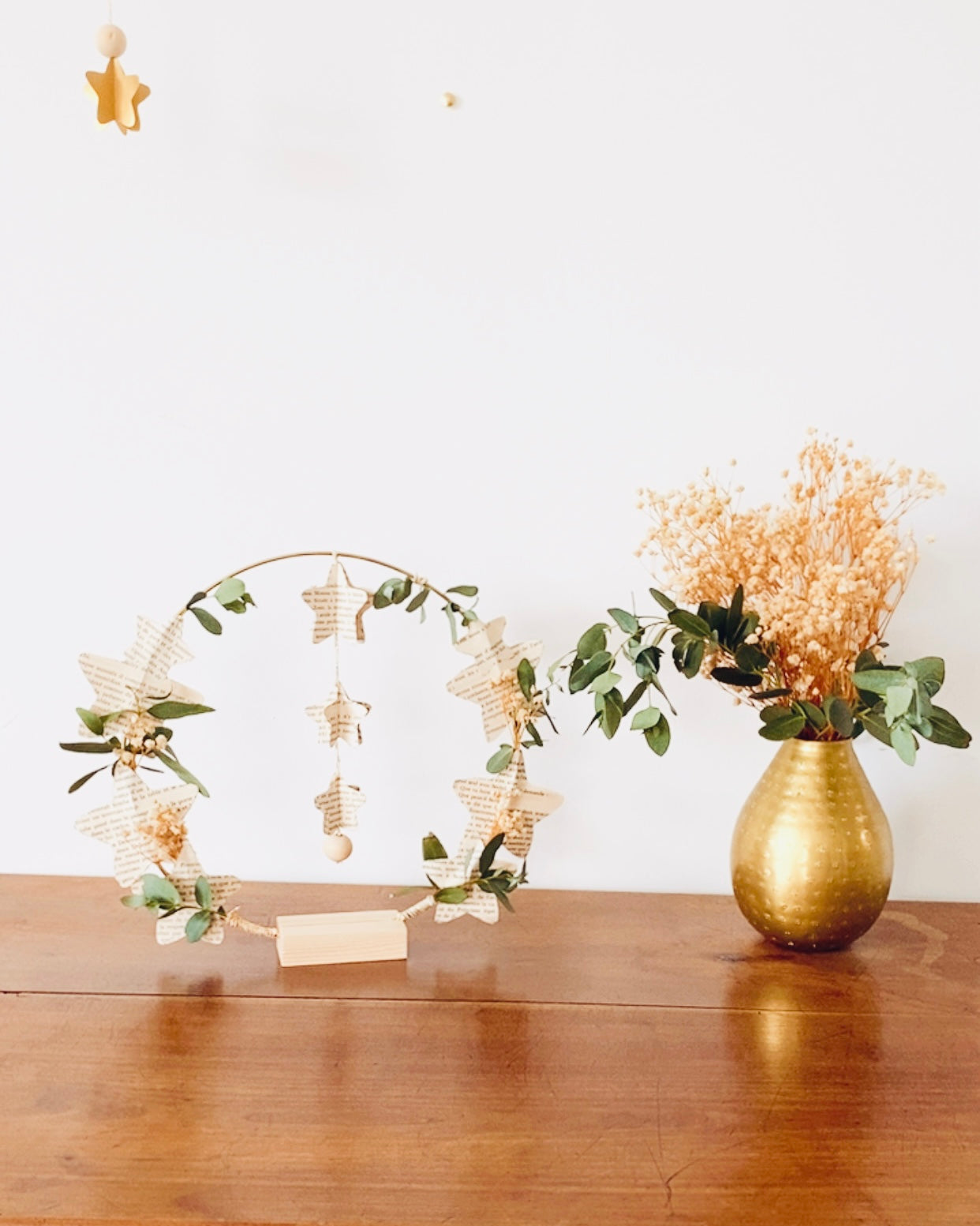 Couronne artisanale poétique à suspendre, composée de papier de vieux livres découpé en étoiles et de véritables végétaux séchés. Les éléments naturels créent une ambiance douce et chaleureuse, idéale pour un intérieur cocooning. Un choix parfait pour offrir en cadeau ou pour personnaliser sa décoration de maison. Peut convenir à une ambiance de Noël, mais aussi à une décoration murale quotidienne. Fabriquée en France avec soin et délicatesse. ninona