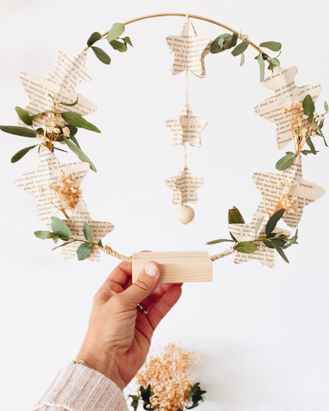 Mobile décoratif tout en légèreté, avec étoiles en papier recyclé et petite touche de fleurs et feuilles séchées. Suspendu, il crée un mouvement subtil et poétique dans la pièce. Il peut être utilisé comme décoration de chambre, de salon ou de fête. Cette création s’inscrit dans une démarche artisanale et écologique, valorisant la récupération de livres anciens. Une pièce unique, faite main en France, au style bohème et intemporel. ninona