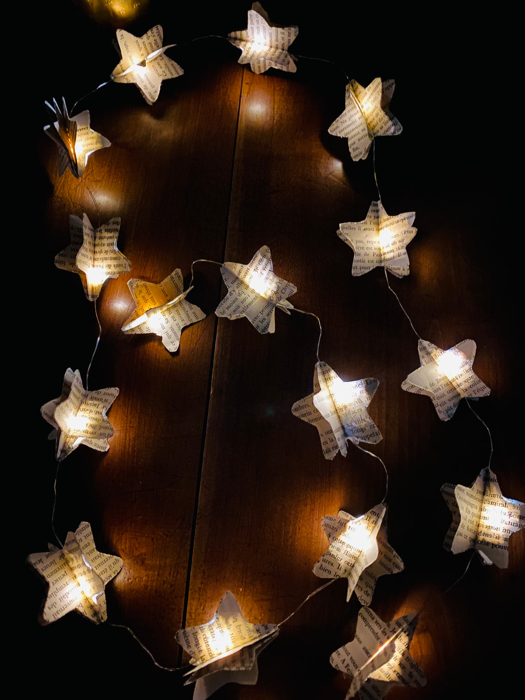 Guirlande décorative faite main composée de 20 étoiles en papier recyclé, decoupées dans de vieilles pages de livres. Chaque étoile est en volume pour créer un effet léger et poétique. La guirlande apporte une ambiance douce, qu’elle soit allumée ou simplement suspendue. Idéale pour une décoration bohème, vintage ou chaleureuse dans un salon, une chambre ou un espace détente. ninona