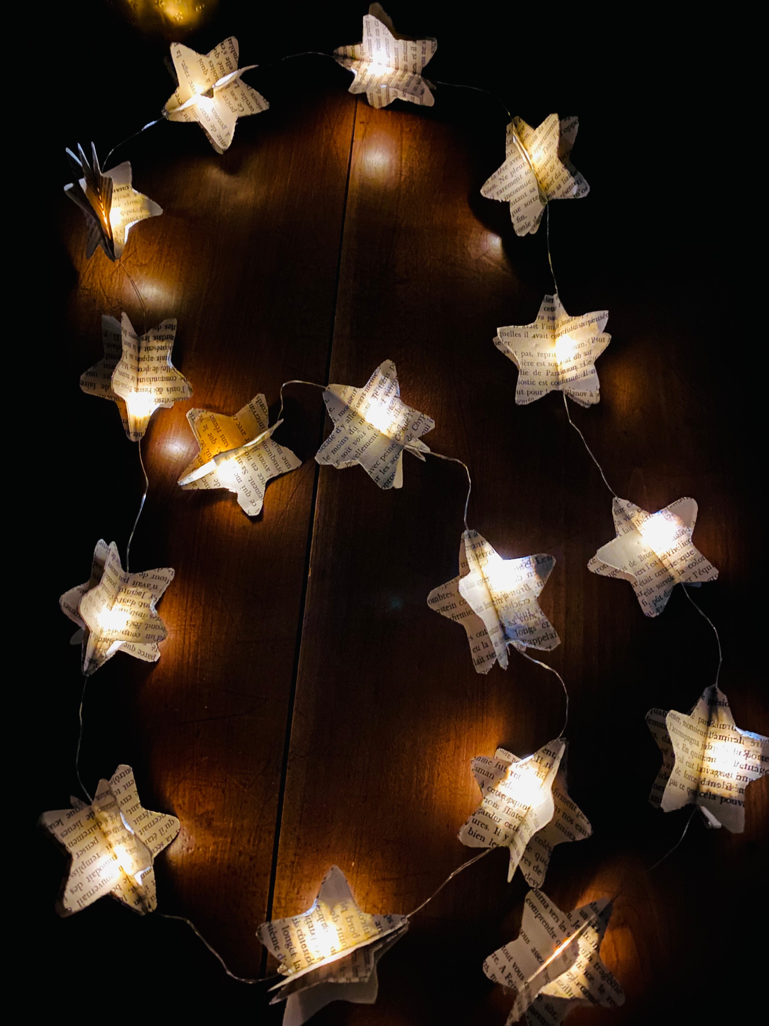Guirlande décorative faite main composée de 20 étoiles en papier recyclé, decoupées dans de vieilles pages de livres. Chaque étoile est en volume pour créer un effet léger et poétique. La guirlande apporte une ambiance douce, qu’elle soit allumée ou simplement suspendue. Idéale pour une décoration bohème, vintage ou chaleureuse dans un salon, une chambre ou un espace détente. ninona