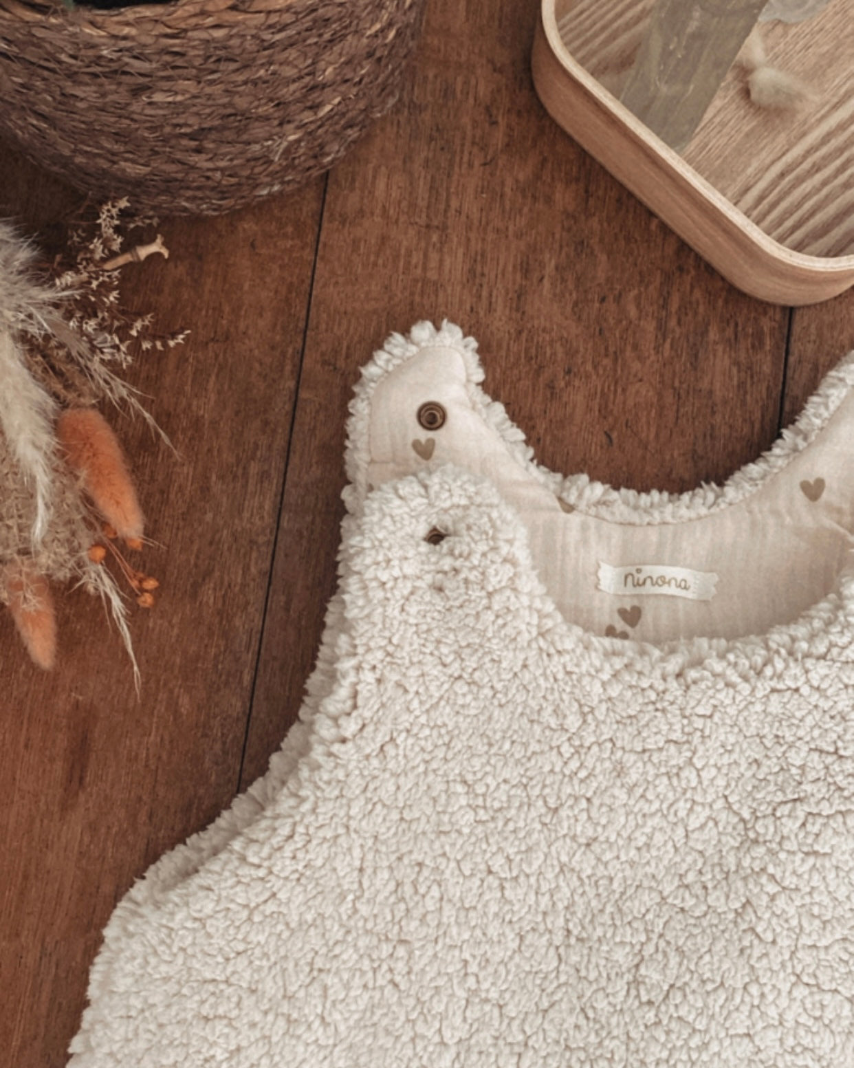 Gigoteuse d’hiver en sherpa et double gaze de coton pour bébé, coloris écru naturel avec petits cœurs beige. Confortable, chaude et respirante, elle offre un cocon douillet idéal pour les nuits hivernales. Fermeture pratique par pressions aux épaules. Parfaite comme cadeau de naissance ou pour assurer des nuits paisibles à bébé tout en douceur. Style bohème, matières naturelles et moelleuses