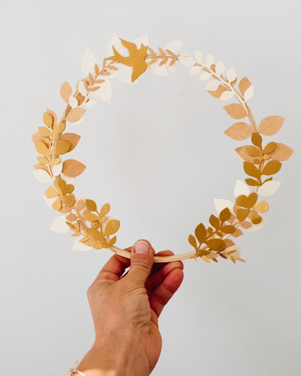 Couronne en papier réalisée à la main, mêlant feuilles, fleurs et couleurs douces pour une décoration murale délicate. Sa structure légère en bois et son style naturel en font un objet parfait pour un intérieur minimaliste, un événement ou un cadeau unique. Chaque pièce est fabriquée entièrement à la main, offrant une création raffinée, poétique et personnalisable selon vos envies. ninona