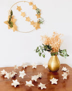 Vue détaillée de la guirlande lumineuse étoiles en papier de livres anciens. Les étoiles sont assemblées à la main et montées sur une guirlande LED à lumière chaude. La texture du papier et le relief donnent un aspect artisanal et poétique. Une décoration éco-responsable qui apporte douceur et charme à une pièce, parfaite pour une chambre ou un coin lecture. ninona