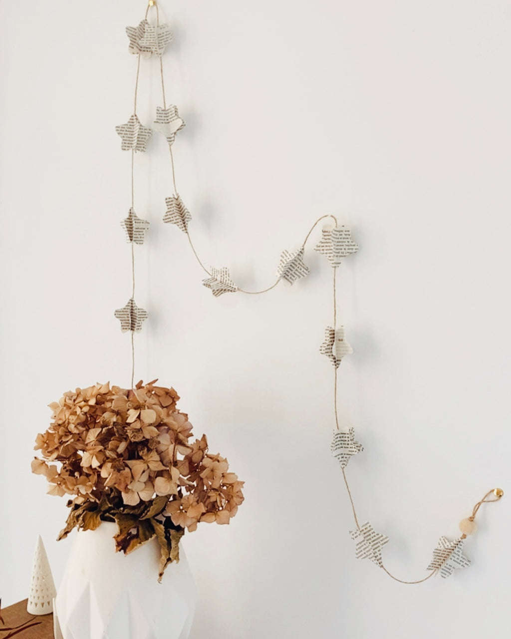 Suspendue entre mots et lumière, cette guirlande d’étoiles en pages de vieux livres réinvente les histoires passées. Chaque étoile, pliée à la main, semble s’échapper d’un roman ancien pour danser dans l’air. Reliées par un fil de jute et deux perles de bois naturel, elles offrent une poésie discrète, douce et intemporelle à tout espace qu’elles habitent. ninona