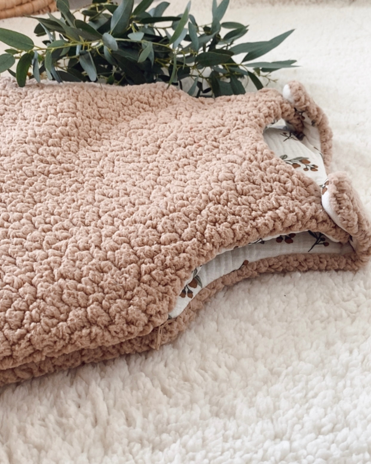 Gigoteuse d’hiver artisanale en sherpa beige, doublée en double gaze de coton imprimée de petites branches florales. Avec son indice TOG 2, elle garde bébé bien au chaud tout l’hiver. Convient aux bébés de 0 à 6 mois. Son style doux et naturel s’intègre parfaitement dans une chambre de bébé apaisante. Cette gigoteuse faite main est un cadeau de naissance idéal, mêlant esthétique, confort et sécurité pendant le sommeil.