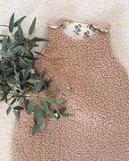 Gigoteuse d’hiver artisanale en sherpa beige, doublée en double gaze de coton imprimée de petites branches florales. Avec son indice TOG 2, elle garde bébé bien au chaud tout l’hiver. Convient aux bébés de 0 à 6 mois. Son style doux et naturel s’intègre parfaitement dans une chambre de bébé apaisante. Cette gigoteuse faite main est un cadeau de naissance idéal, mêlant esthétique, confort et sécurité pendant le sommeil.