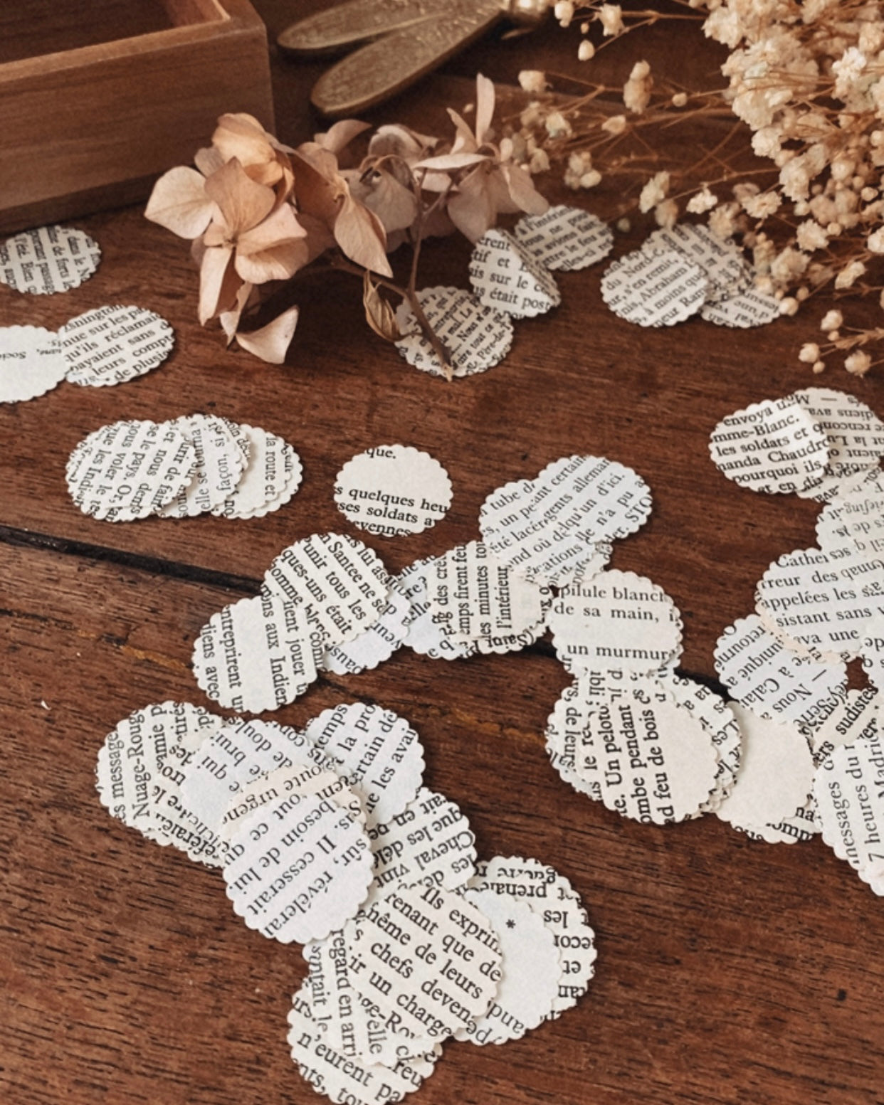 Gros plan sur des confettis ronds fabriqués à partir de pages de livres anciens. On distingue clairement la texture du papier, les variations de teinte et les caractères typographiques imprimés, rendant chaque pièce unique. Le papier a un aspect naturel et patiné, typique des livres vintage. Ces confettis faits main apportent une touche authentique et élégante à une décoration de table éco-responsable. ninona création
