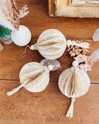 Optez pour une décoration de Noël artisanale avec cette boule en papier recyclé. Chaque exemplaire est fait main à partir de livres anciens, valorisés grâce à l’upcycling. Ses détails en bois et sa finition naturelle en font une création douce et durable. Idéale pour un intérieur chaleureux, minimaliste, bohème ou vintage. Une alternative éco-responsable aux décorations classiques. ninona