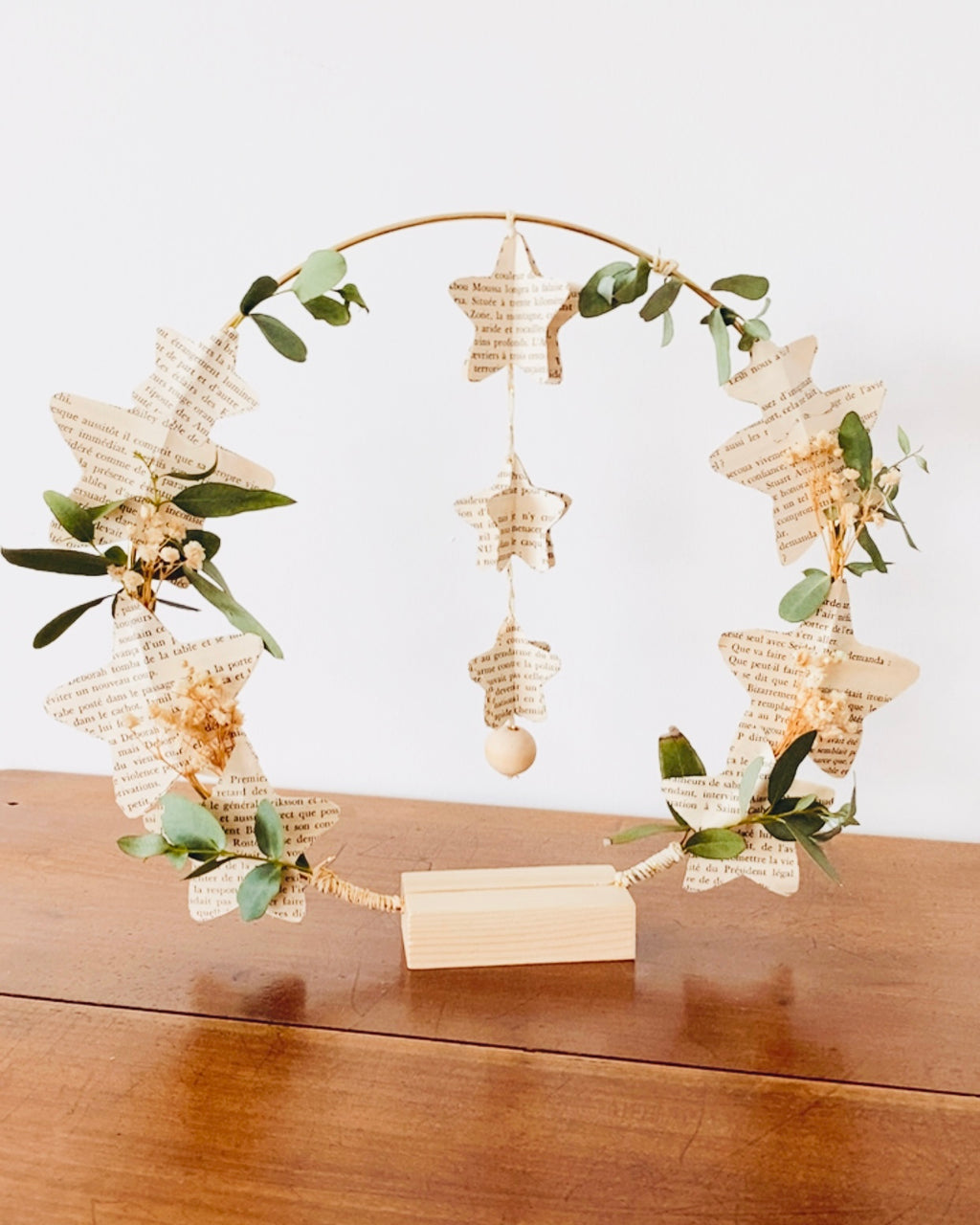 Décoration murale délicate en fleurs séchées et papier recyclé provenant de livres anciens. Les étoiles en papier apportent une touche poétique, tandis que les feuilles d’eucalyptus apportent une atmosphère apaisante et végétale. Parfaite pour un intérieur bohème, minimaliste ou naturel. Peut être utilisée en centre de table, décoration de fête ou pièce décorative quotidienne. Création artisanale française, faite à la main avec amour et délicatesse. ninona