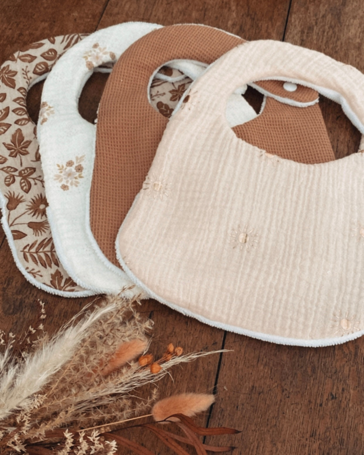 Lot artisanal de bavoirs bébé faits main en coton, gaze de coton et tissu absorbant. Chaque bavoir est doux, pratique et confortable pour la peau délicate de bébé. Fermeture par bouton pression sécurisée, idéale dès la naissance. Motifs assortis aux tons naturels et floraux bohèmes. Un lot de bavoirs élégants et absorbants, parfaits pour les repas ou les bavouilles quotidiennes. Accessoire pratique et esthétique, idéal comme cadeau de naissance ou baby shower