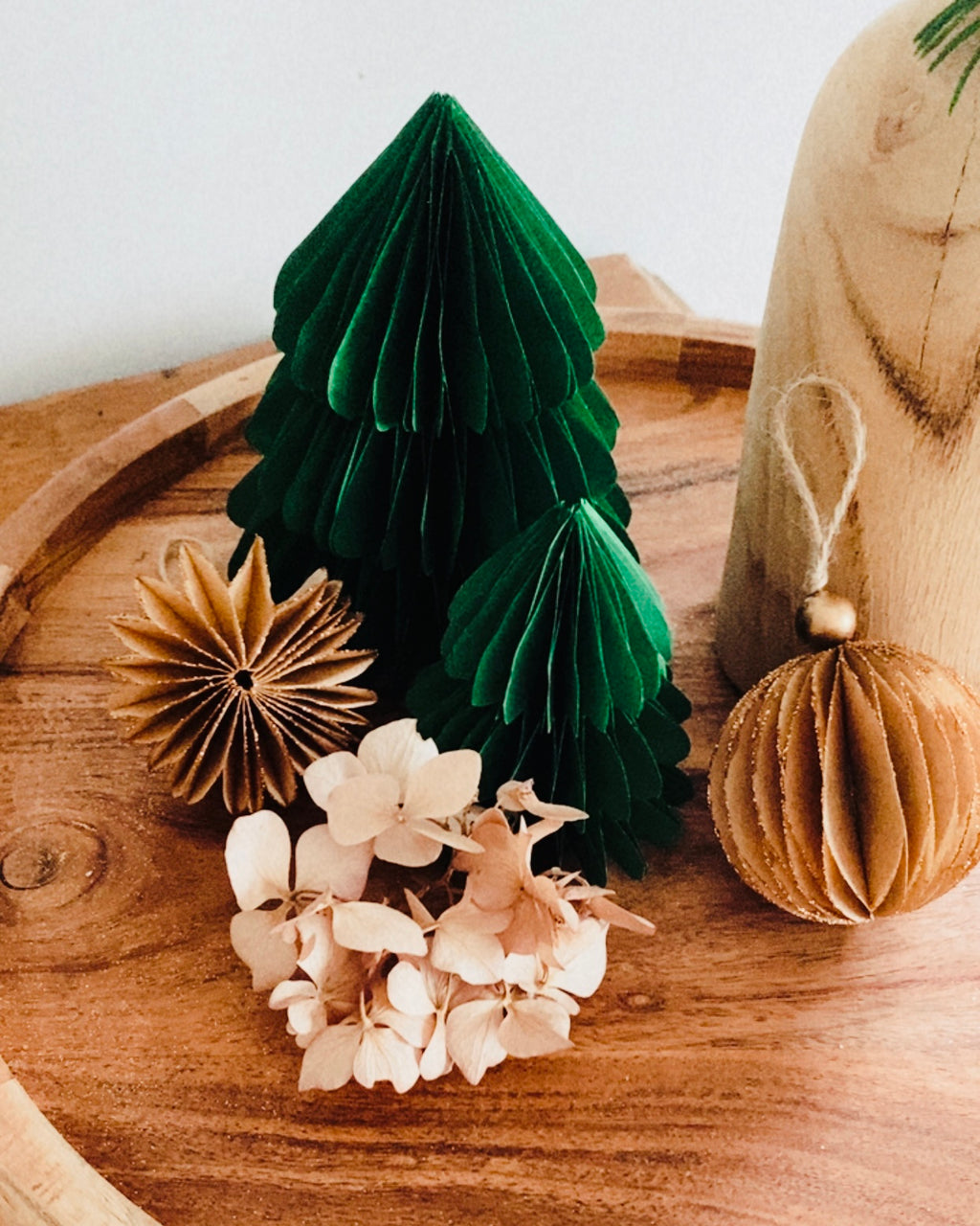 Lot de deux sapins en papier faits main, en vert émeraude, posés sur un plateau en bois dans une ambiance douce et chaleureuse. Ces décorations artisanales de Noël apportent une touche poétique et naturelle à votre intérieur. Idéal pour compléter une décoration de table, créer un village d’hiver miniature ou offrir un cadeau fait avec soin. ninona
