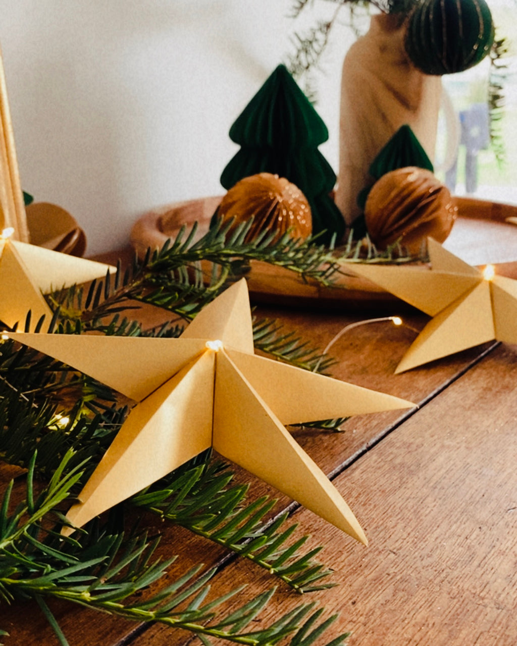 Guirlande d’étoiles en papier doré fixée près d’un miroir ancien. Lumière LED douce créant une ambiance chaleureuse et accueillante. Chaque étoile est réalisée à la main avec soin, inspirée de l’artisanat et de la décoration naturelle. Parfait pour le salon, une chambre d’enfant, ou pour créer une atmosphère de Noël douce et lumineuse. Décoration élégante et poétique. ninona