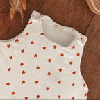 Zoom sur le haut d’une gigoteuse bébé écrue en double gaze de coton, décorée de petits cœurs rouges. On distingue le col arrondi, les emmanchures et les deux pressions placées aux épaules pour faciliter l’habillage. La matière est douce et légèrement gaufrée, avec un intérieur en double gaze de coton. Cette turbulette d’hiver TOG 2 convient aux bébés de 0 à 6 mois. Un modèle délicat et intemporel, idéal pour les nuits fraîches. Une finition délicate qui souligne le soin apporté à chaque détail ! 