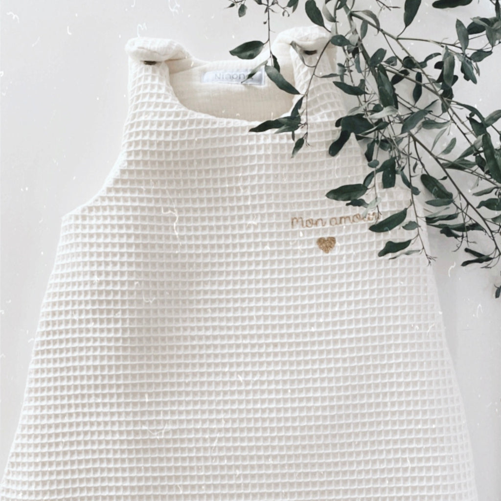 La gigoteuse Ninona est confectionnée à la main dans un tissu en nid d’abeille et double gaze de coton écru. Idéale pour envelopper bébé de douceur, elle remplace la couverture en toute sécurité et favorise un sommeil paisible. Personnalisable avec une jolie broderie, c’est aussi un cadeau unique et tendre. Ninona valorise l’artisanat et propose des créations intemporelles pour accompagner les premiers rêves des tout-petits.
