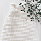 La gigoteuse Ninona est confectionnée à la main dans un tissu en nid d’abeille et double gaze de coton écru. Idéale pour envelopper bébé de douceur, elle remplace la couverture en toute sécurité et favorise un sommeil paisible. Personnalisable avec une jolie broderie, c’est aussi un cadeau unique et tendre. Ninona valorise l’artisanat et propose des créations intemporelles pour accompagner les premiers rêves des tout-petits.