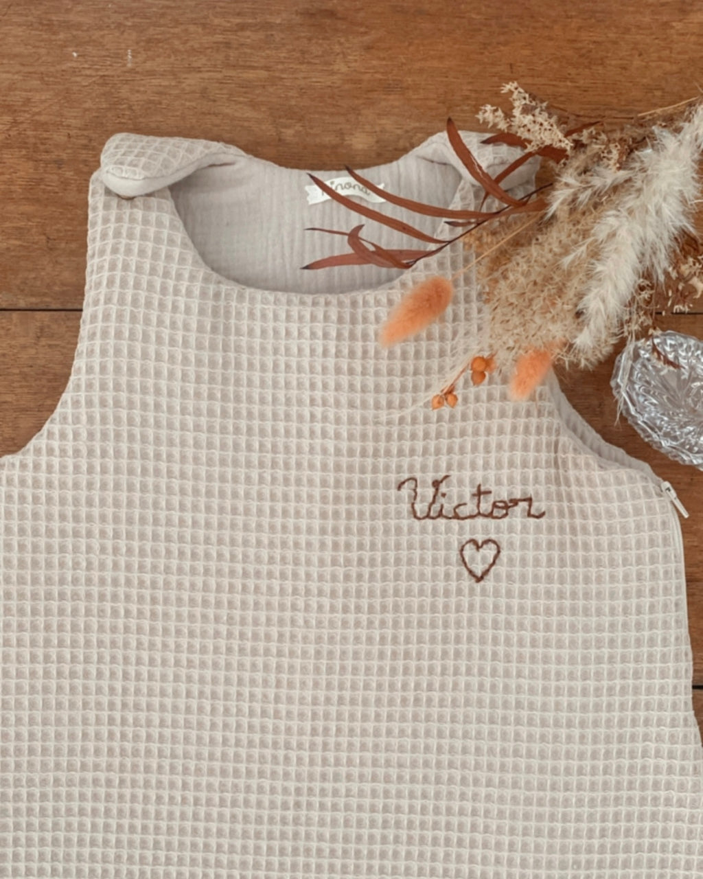 Choisissez la gigoteuse personnalisée Ninona pour offrir à bébé un cocon rassurant et élégant. Fabriquée artisanalement en France en nid d’abeille et double gaze de coton beige, cette gigoteuse bébé garantit confort et sécurité. Cadeau de naissance incontournable, chaque gigoteuse Ninona est personnalisable avec le prénom de l’enfant, faisant de chaque pièce un objet unique, tendre et raffiné, symbole d’artisanat français.