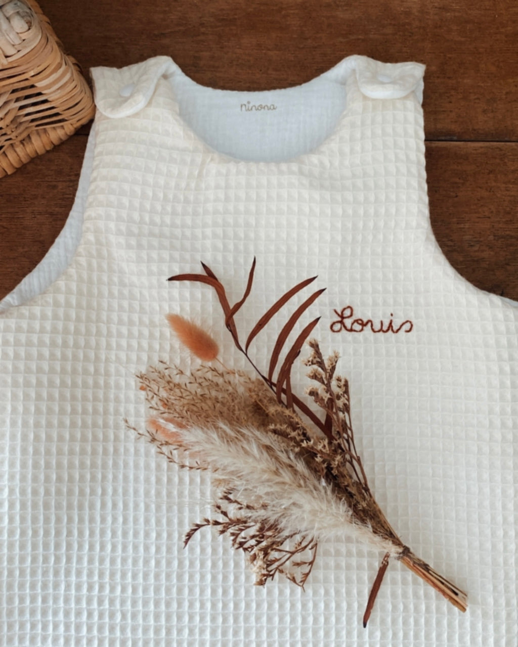 Découvrez la gigoteuse artisanale Ninona en nid d’abeille et double gaze de coton écru. Douce, respirante et sécurisante, elle accompagne les nuits et siestes de bébé avec élégance. Conçue et fabriquée à la main, chaque pièce est unique et personnalisable avec le prénom de l’enfant. Ninona, c’est le choix d’un savoir-faire français alliant confort, qualité et raffinement pour offrir à votre bébé un sommeil apaisé.