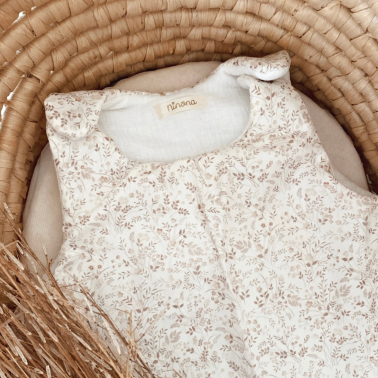 gigoteuse personnalisable pour bébé fille, aux motifs fleuris dans les tons beiges et marron clair. la personnalisation pourra être faite à l'aide d'un flex thermocollant, ou une broderie a la main. Cette gigoteuse est utilisable dès la naissance, elle est disponible en version été, mi saison et hiver. cette turbulette personnalisable pour bébé fille est une belle idée de cadeau de naissance.