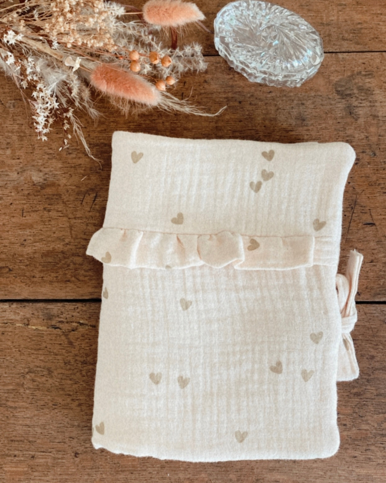 protège carnet de santé personnalisable, dans les tons beiges et écru. Cette housse de carnet de sante personnalisable est réalisée avec une double gaze de coton, avec des petits coeurs dorés.  De jolis froufrou ajoutent une touche de poèsie à cette housse de carnet de santé. Idéal comme cadeau de naissance pour une petite fille.
